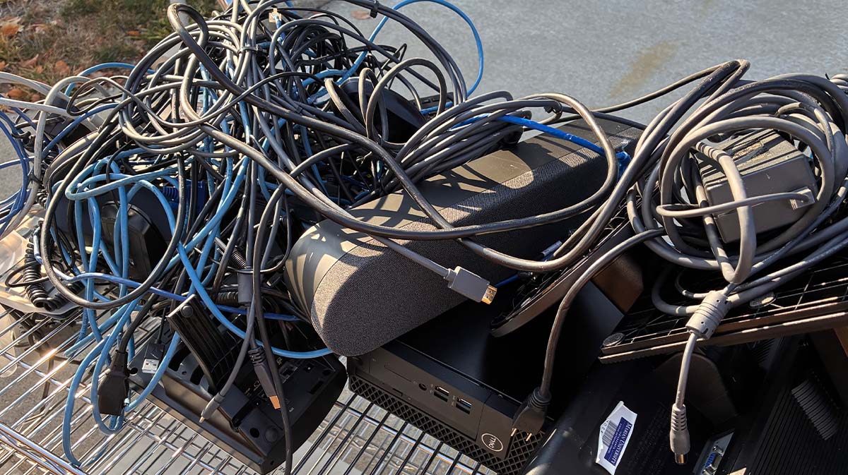 A tangled mess of various electronic cables and adapters on a cart.