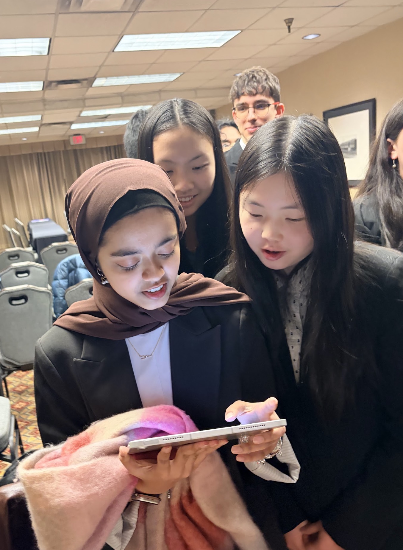 A group of three young women engaged in looking at a tablet together, showcasing enthusiasm and collaboration.
