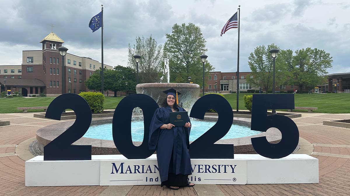 Marian University graduate in front of fountain