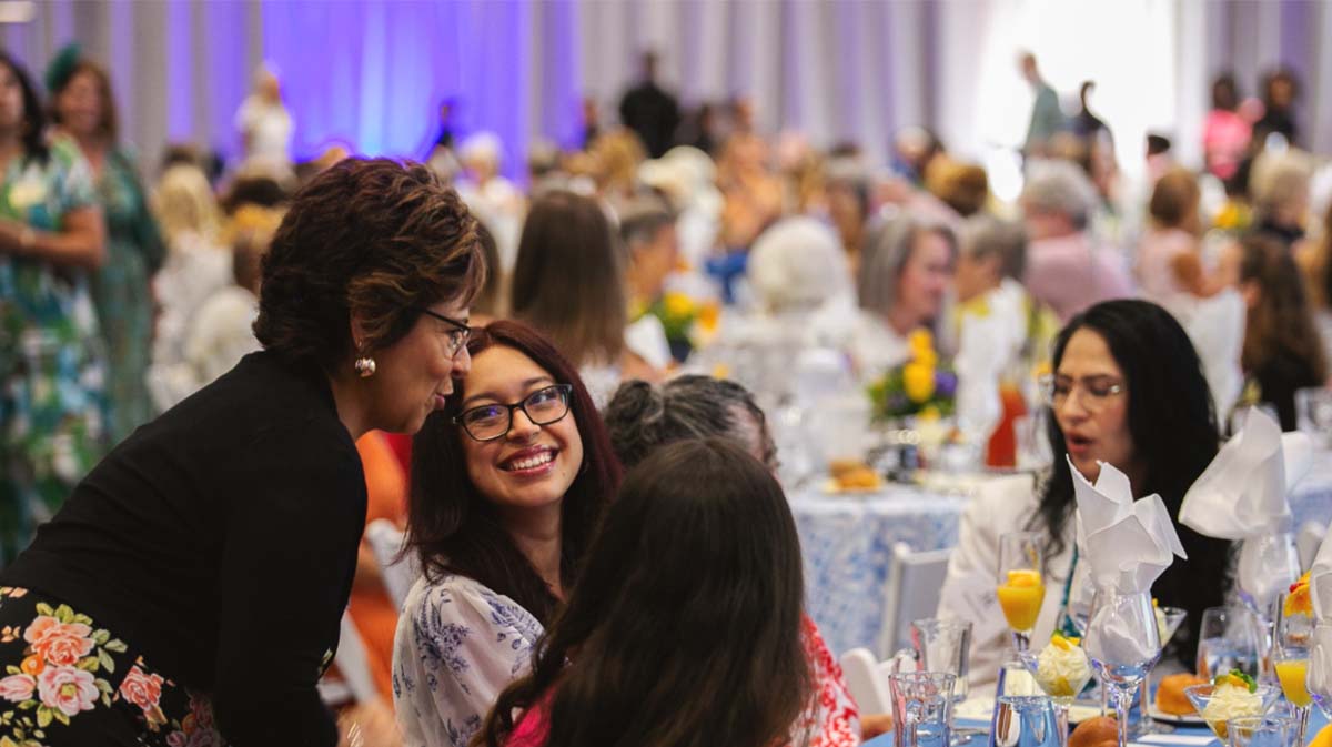 A lively banquet scene featuring women engaged in conversation while enjoying a formal gathering.
