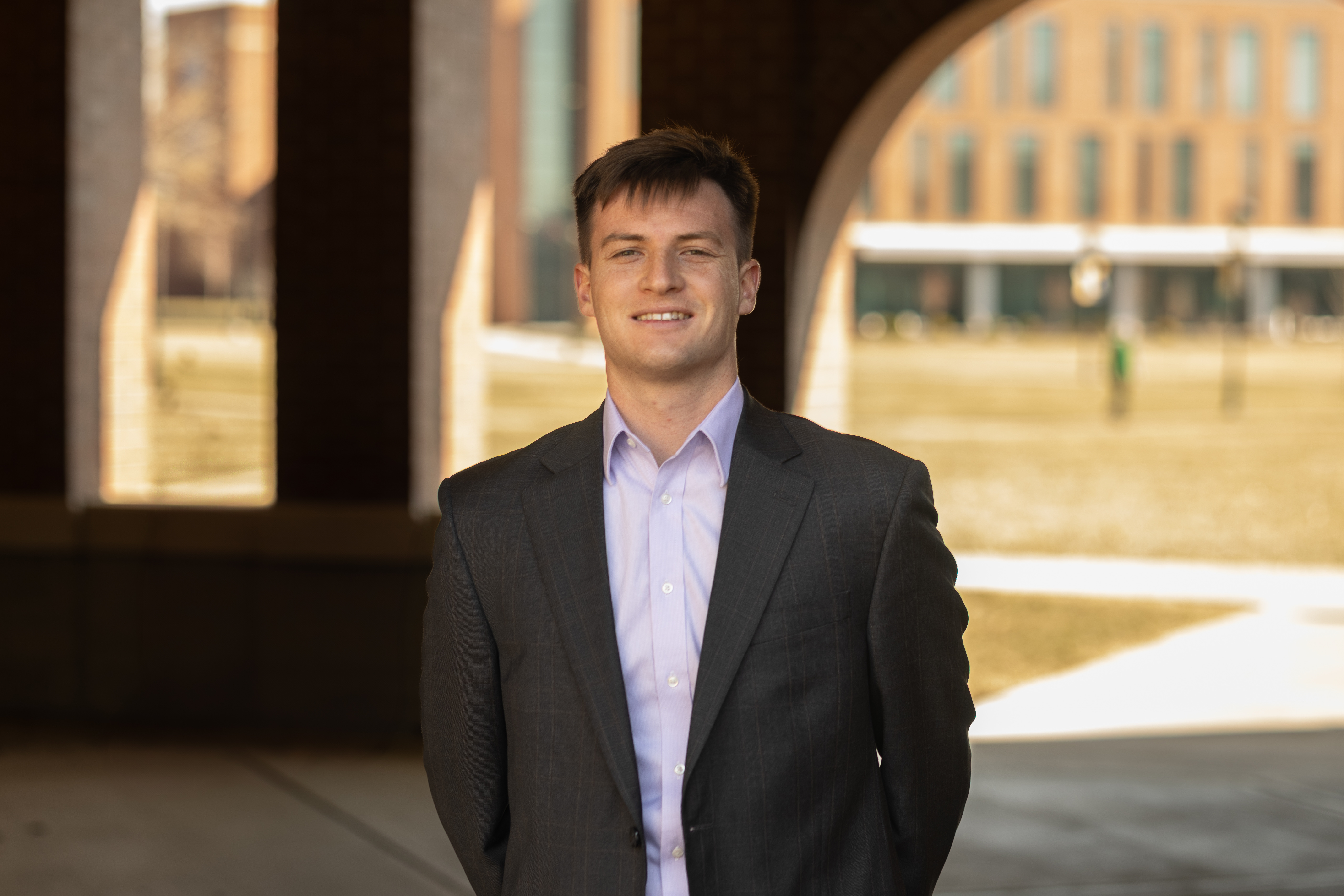 Professional portrait of Zivan Mynhardt in a suit, standing in front of a school emblem.