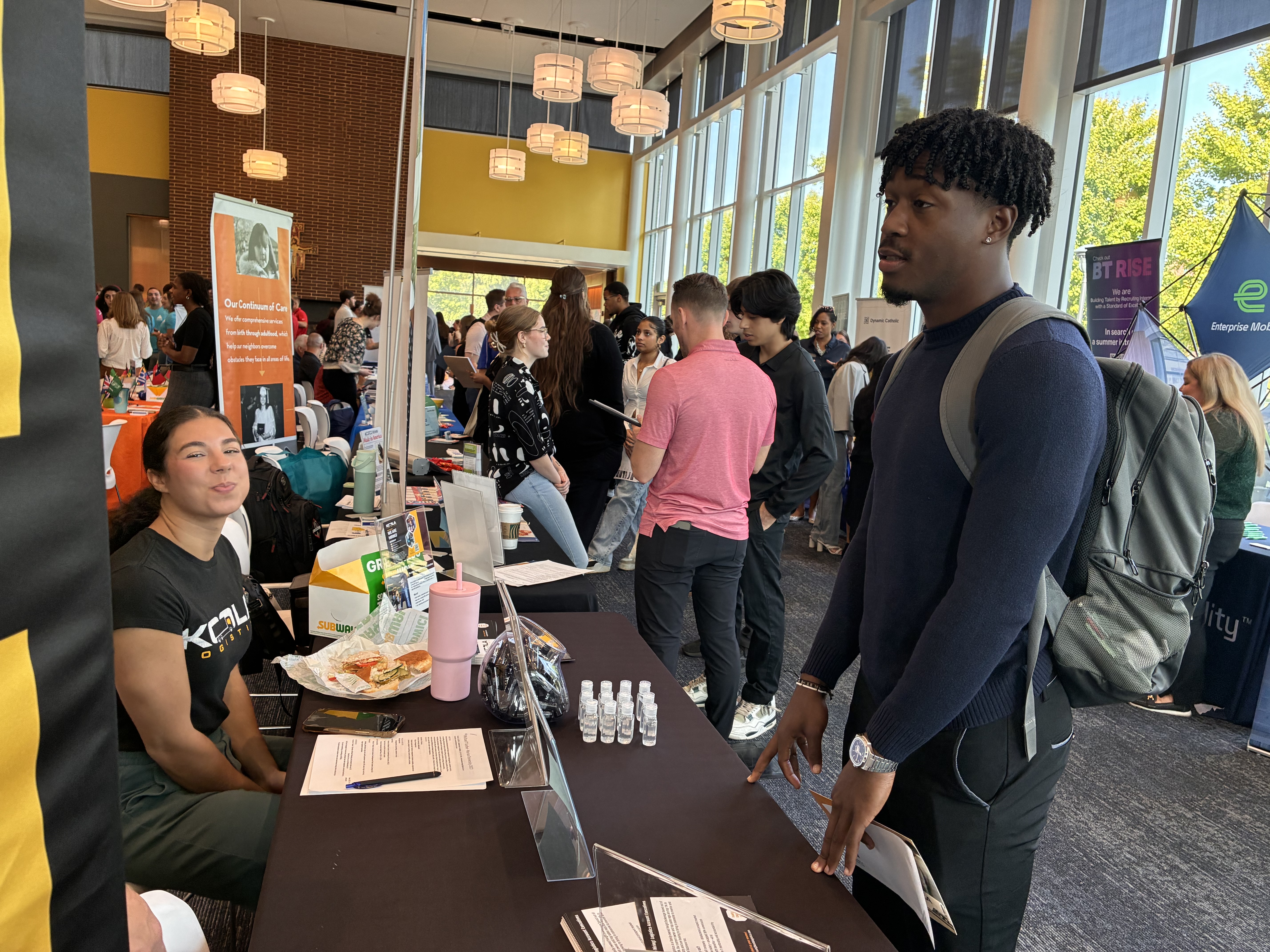 A bustling career fair scene with attendees engaging at various booths, showcasing networking and opportunity.