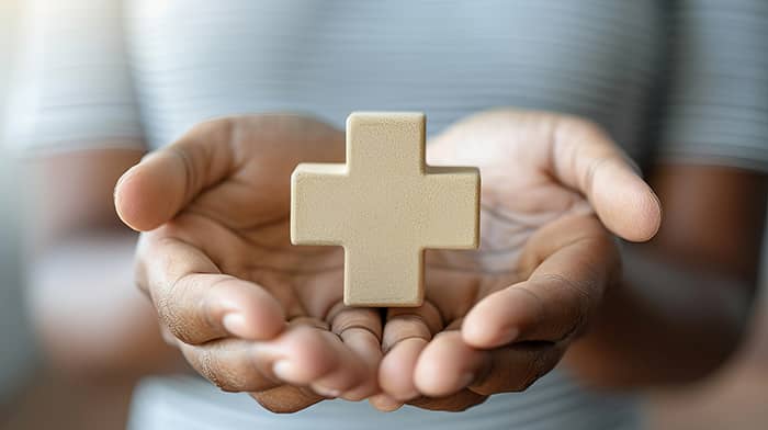 Close up of hands with a cross floating above them