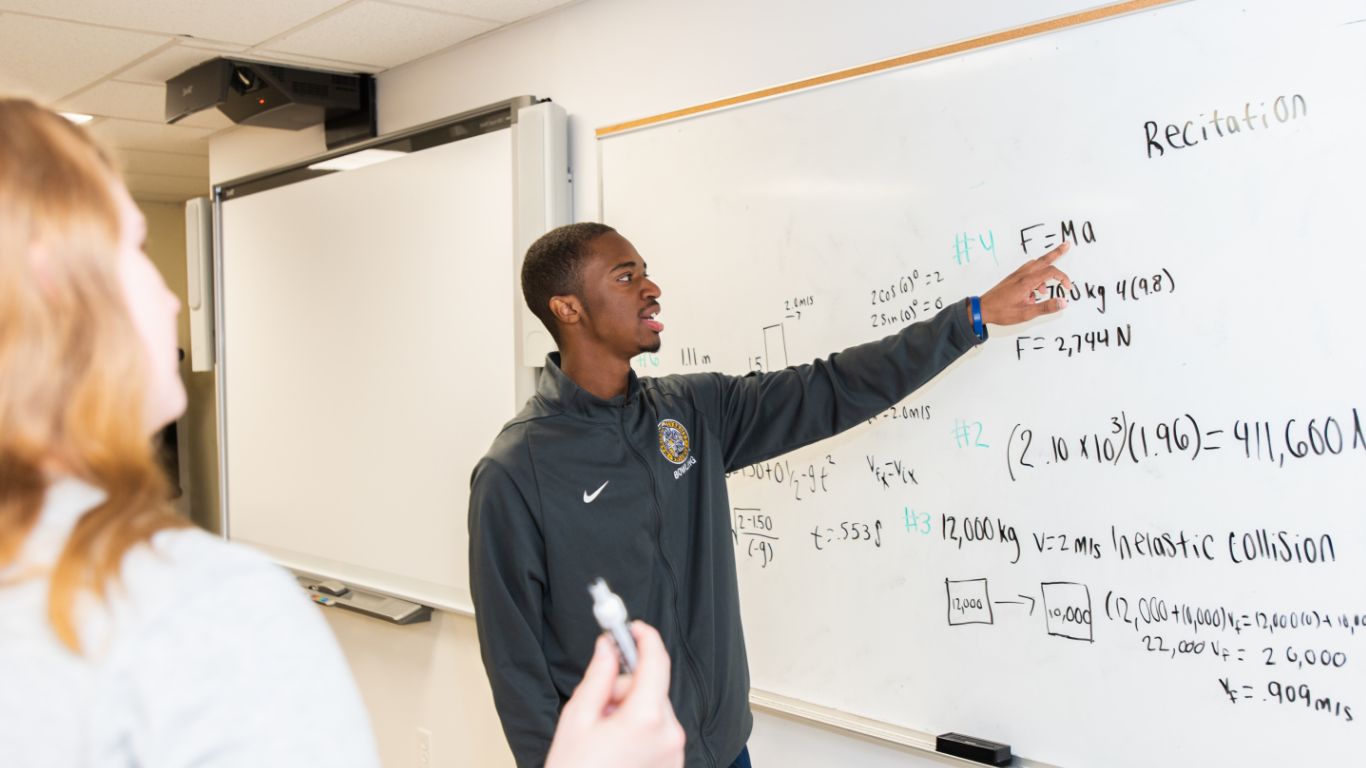 Civil engineering student pointing at science equation on whiteboard