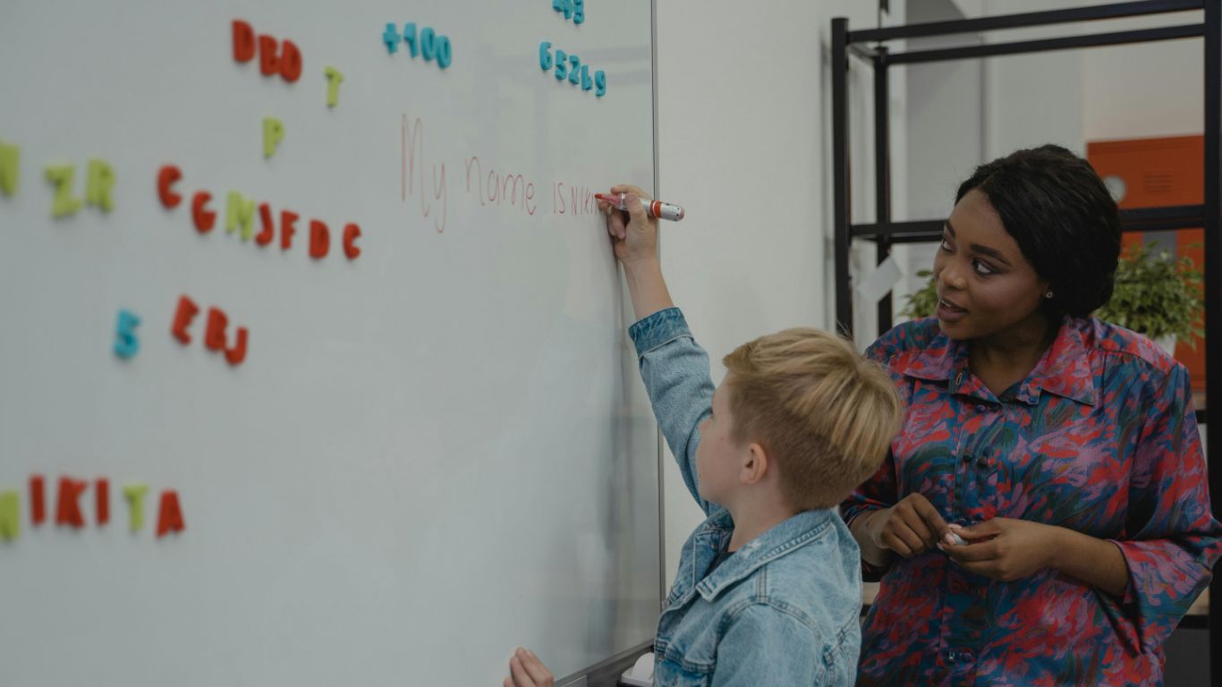 Professor and student writing on whiteboard