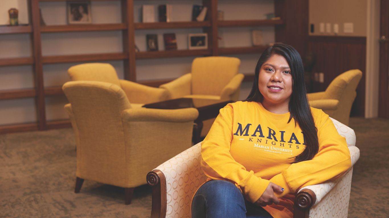 Student with Marian shirt smiling in library