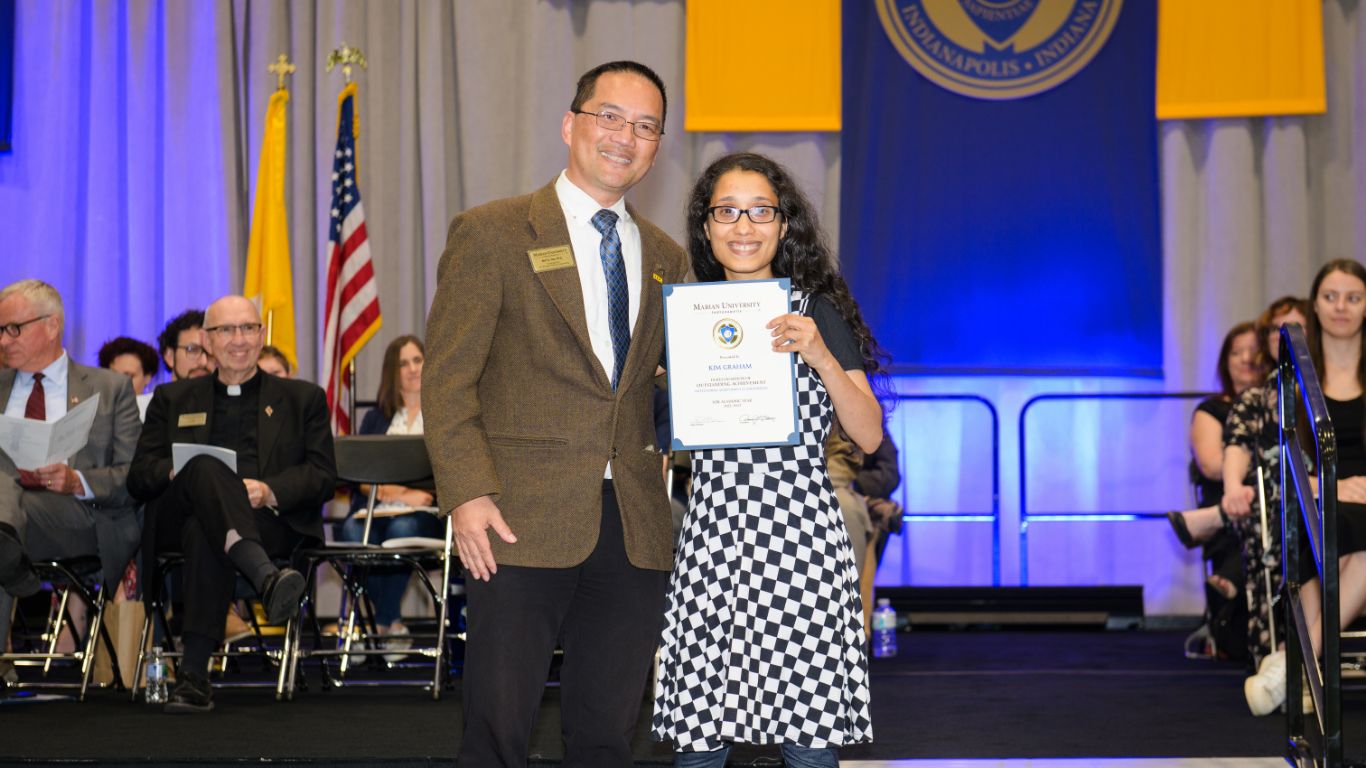 Student and administrator posing on stage