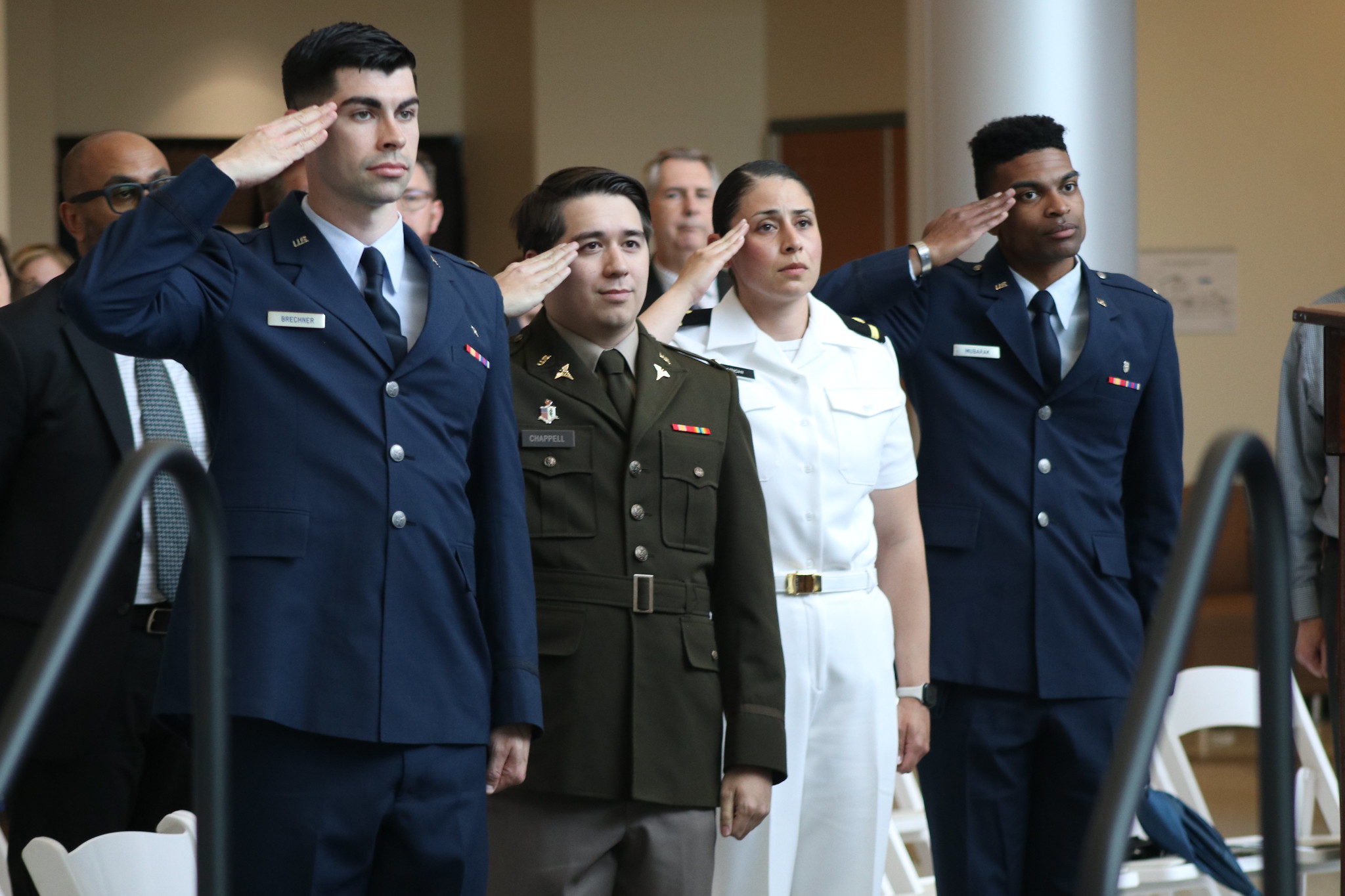 Three students, two wearing Marian University merchandise, smile together in front of a stadium with "Go Knights" displayed prominently.