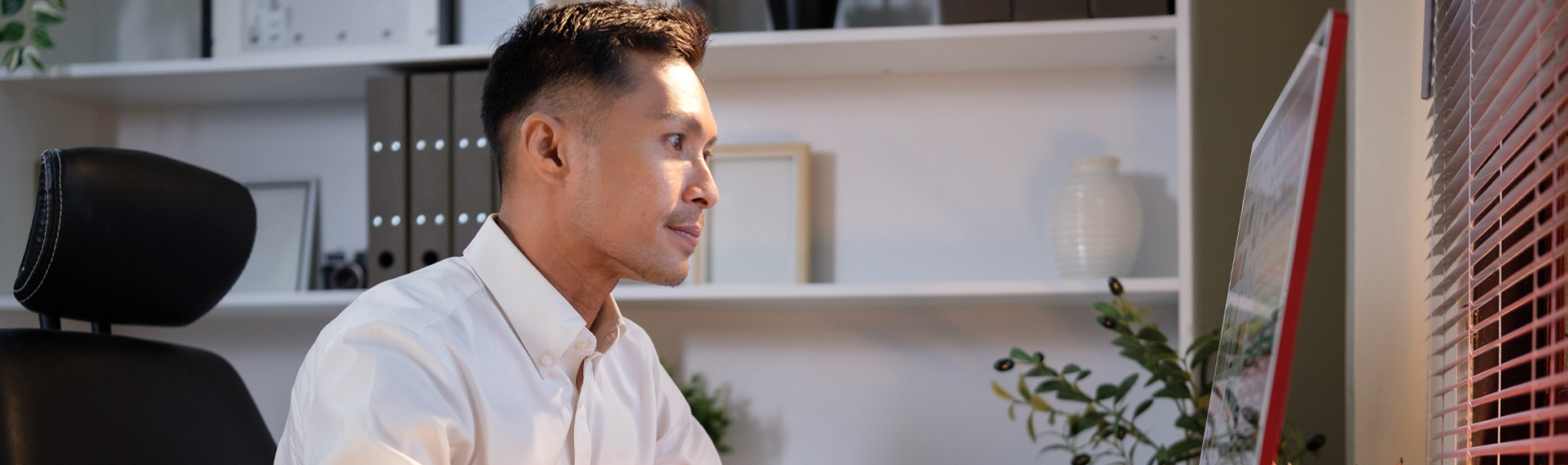 Professional man in a white shirt working at a computer in a modern office.