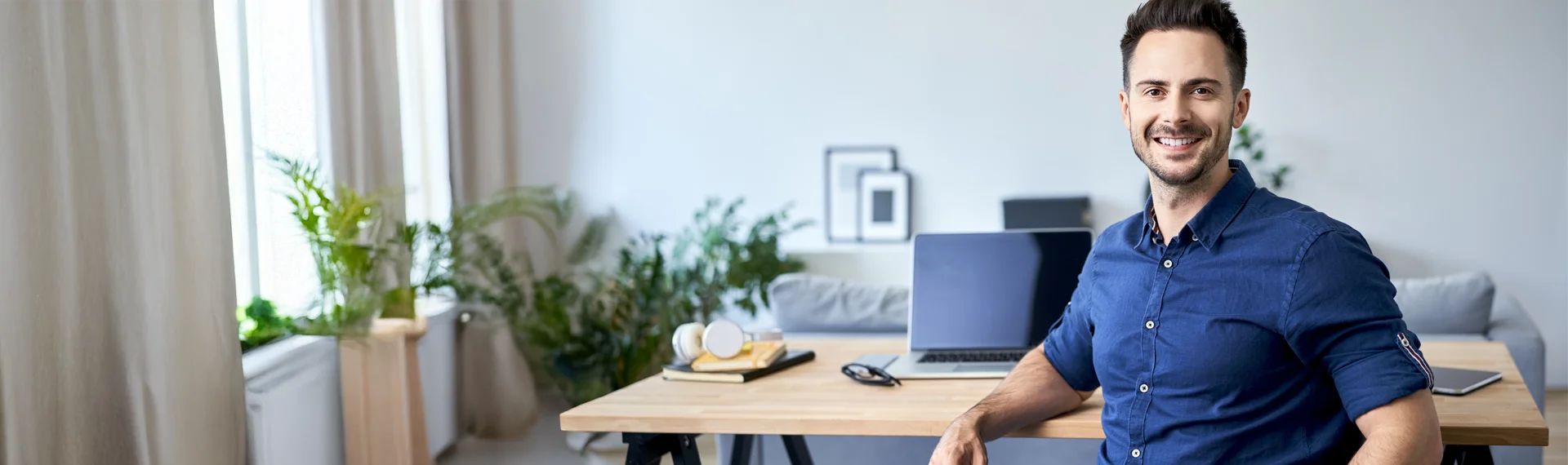 Smiling professional man working at a home office desk with laptop, representing the comprehensive student support provided in Marian University’s online programs