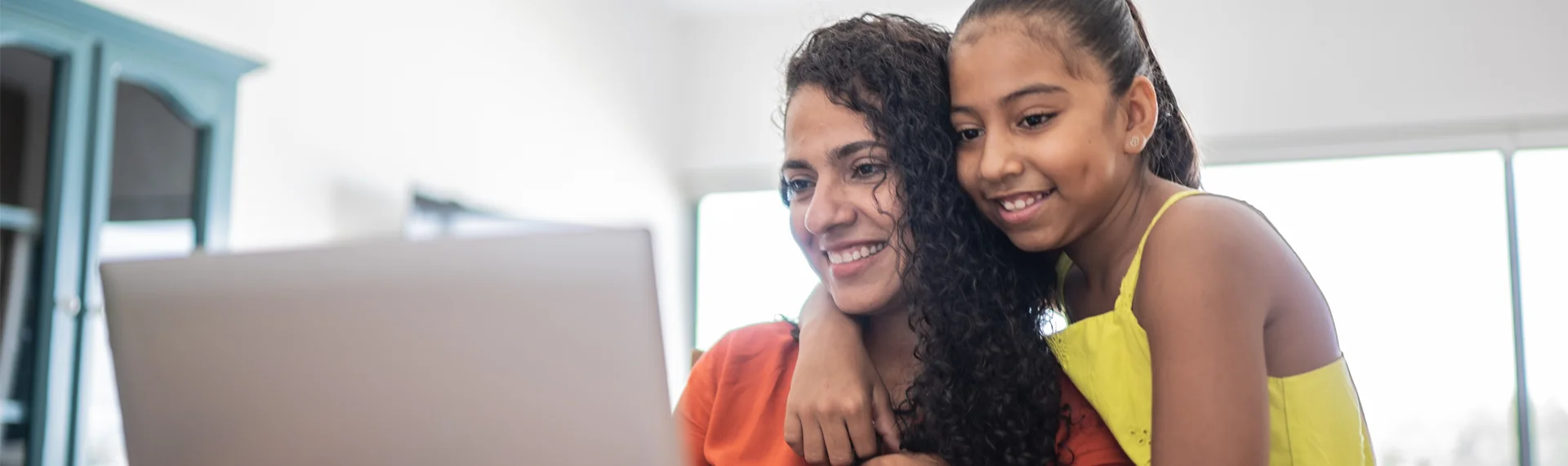 Smiling mother and daughter looking at a laptop together, representing Marian University’s College Pathways Model supporting justice-involved mothers through education and family success