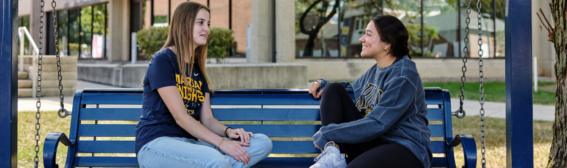 Marian students talking on a bench outside