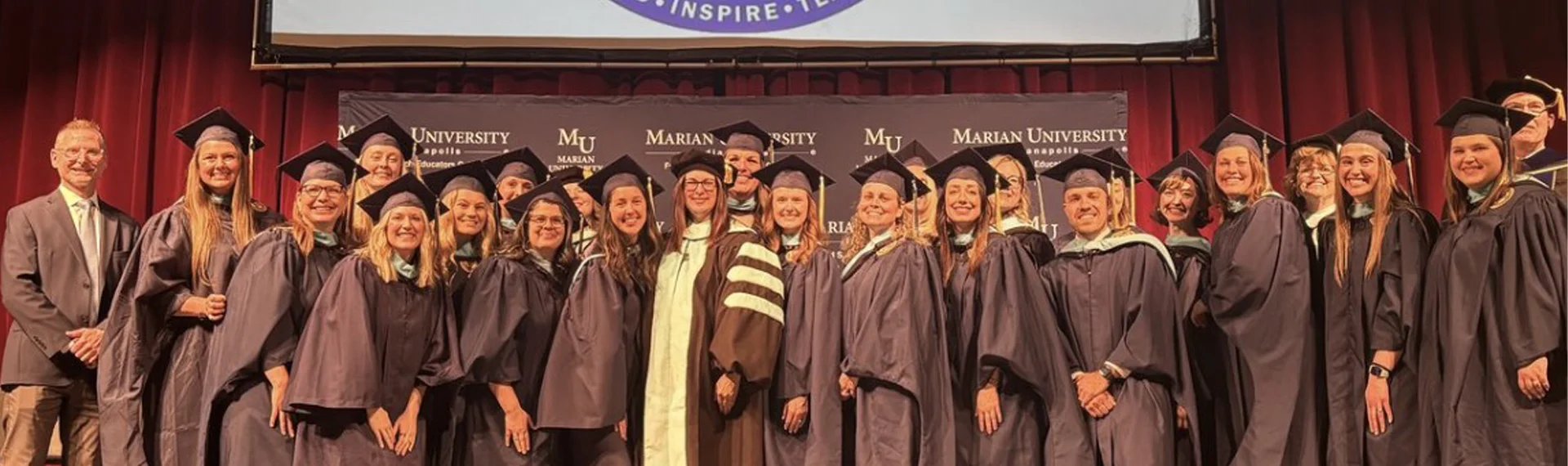 Marian University graduates and faculty celebrating the first MS in Reading Science cohort on stage during commencement, marking a milestone in literacy leadership