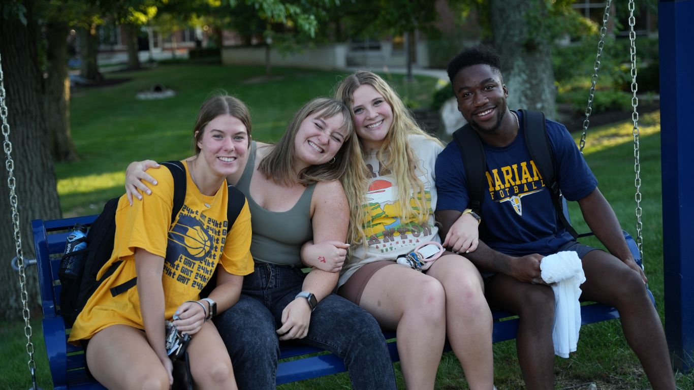 Students sitting on a swing together on campus