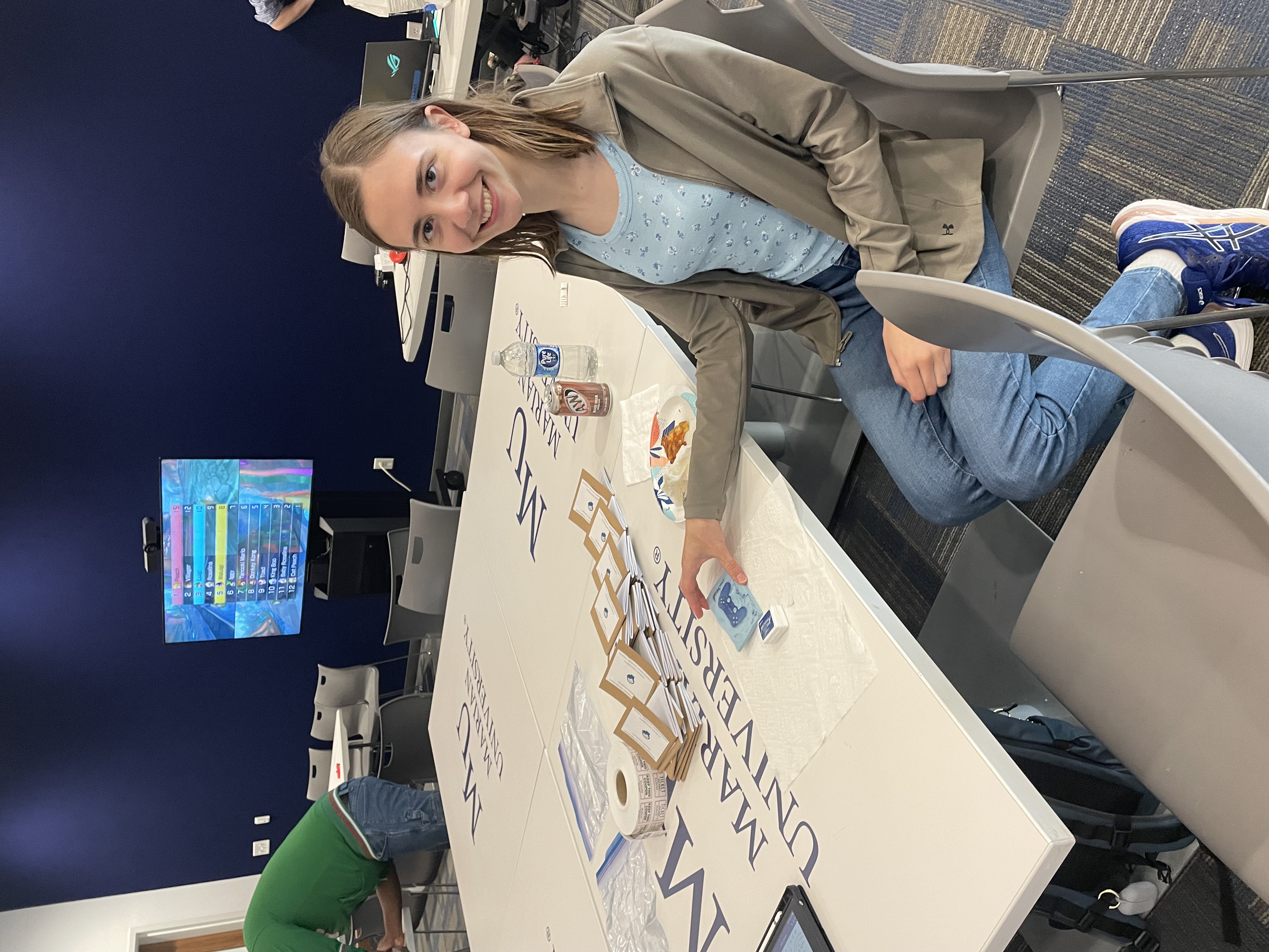 A student is seated at a conference table with the logo of Marietta University visible...