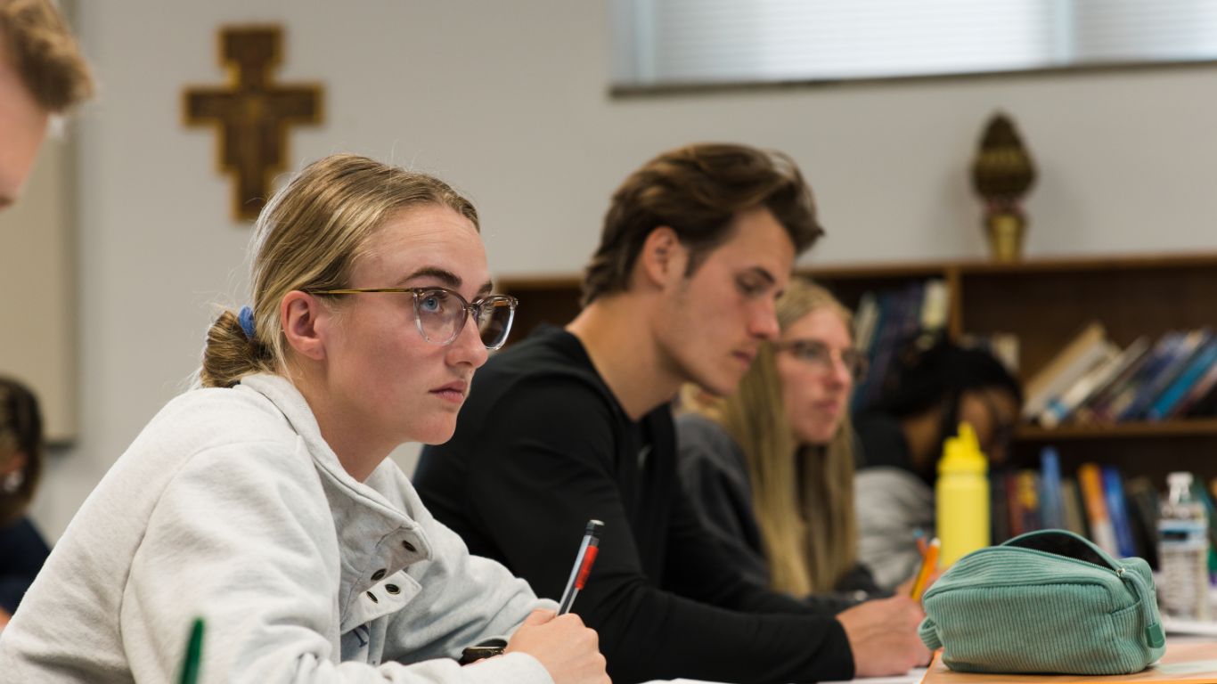 Students engaged in a classroom setting, focused on their work and taking notes.