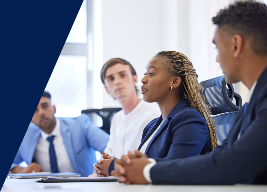 Business team in a meeting as a woman speaks while colleagues listen.