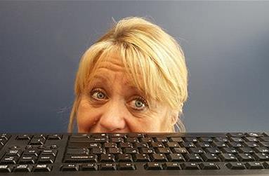 Woman peeking out behind a keyboard