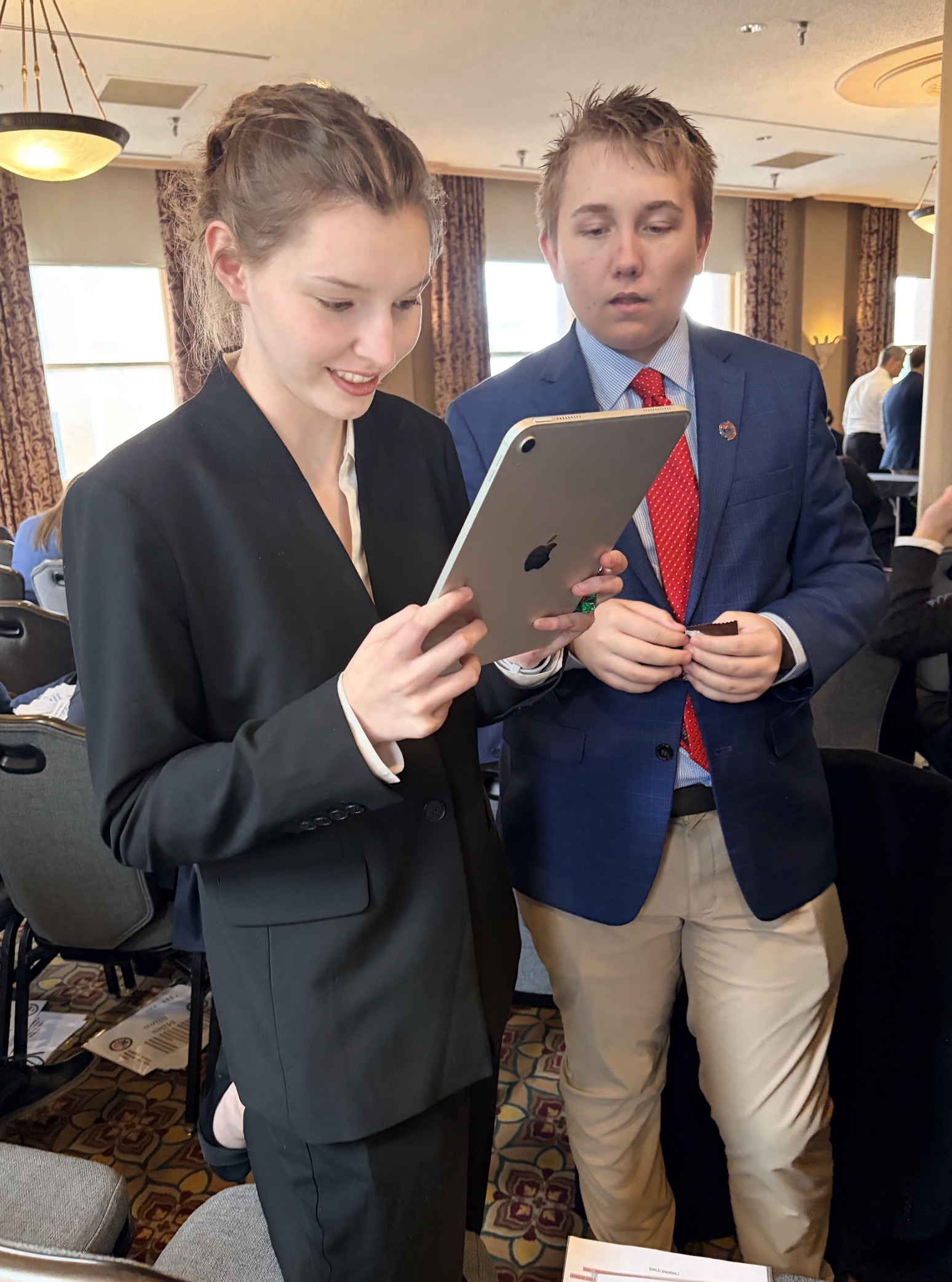 Two young professionals engaged in a discussion while looking at a tablet.