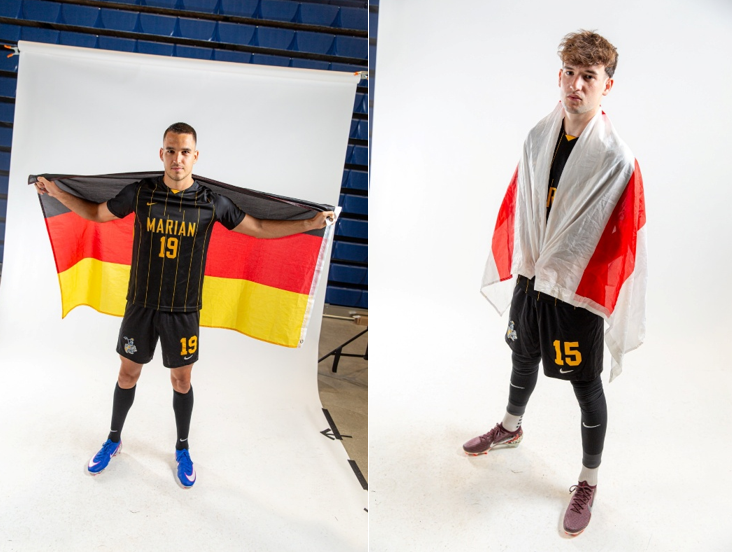 Marian University soccer players Samuel Wehaus holding a German flag and Charlie Piper draped in an English flag.