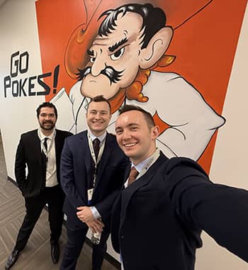 Group selfie in front of huge "Go Pokes" mural with school mascot
