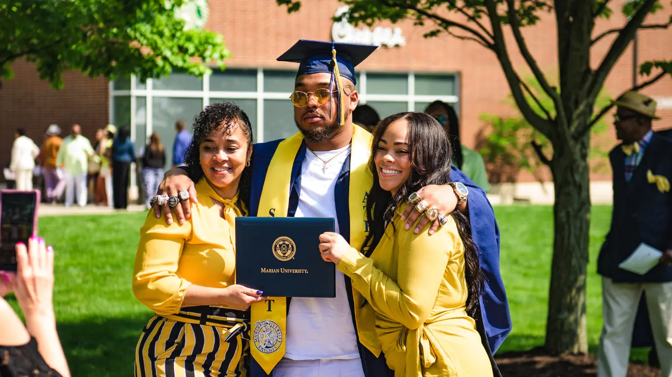 Recent graduate posing for a photo with family