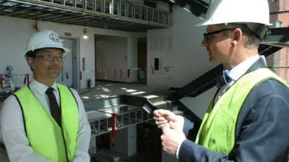 Dr. Ken Britt and Dr. Binh Tran talking while wearing hard hats